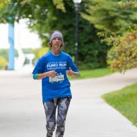 Participant running through campus nearing little mac bridge